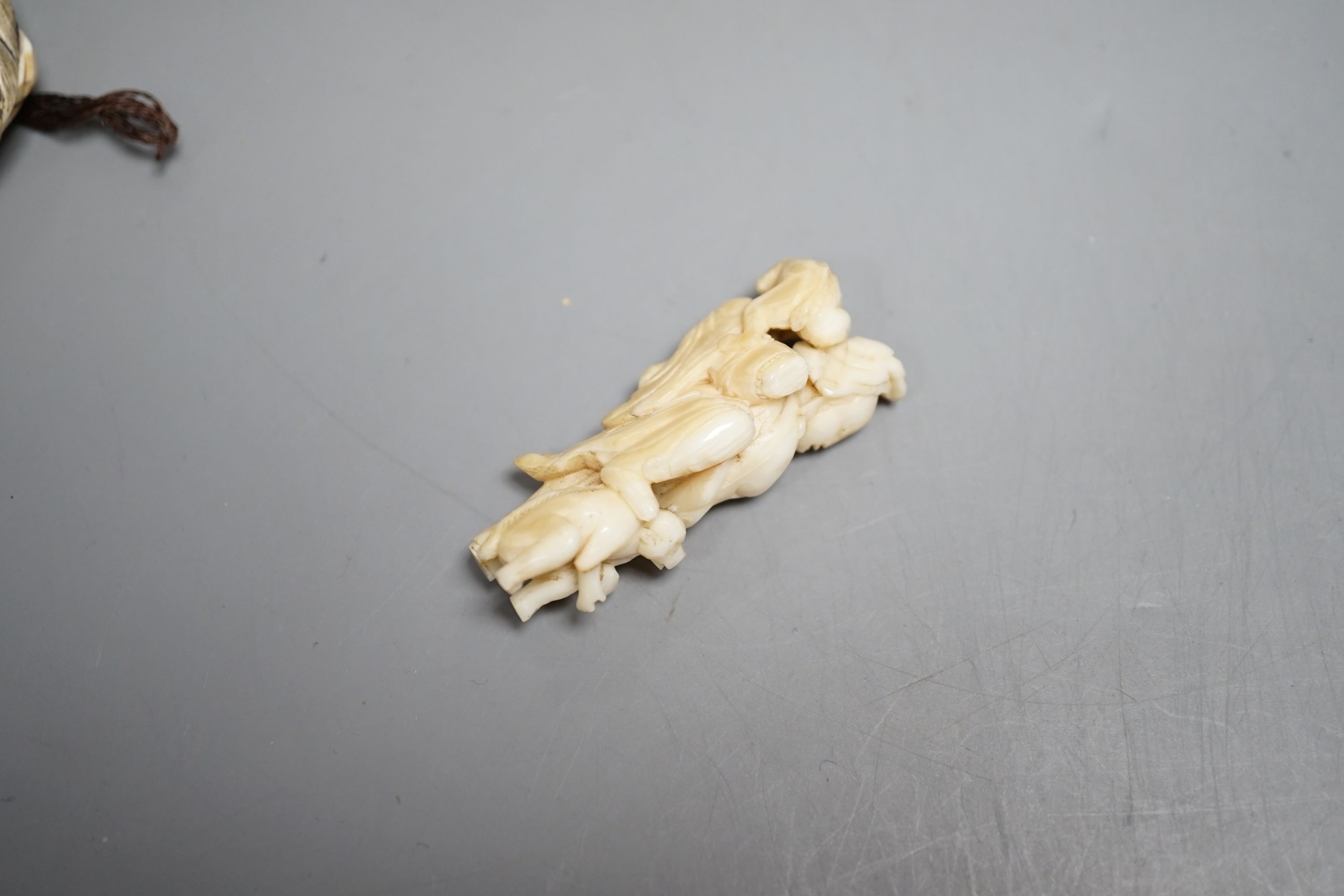 A Japanese ivory netsuke of a man reading a book, a small okimono of Guanyin and monkeys, a Manju netsuke of masks and an early 20th century netsuke of a bearded man